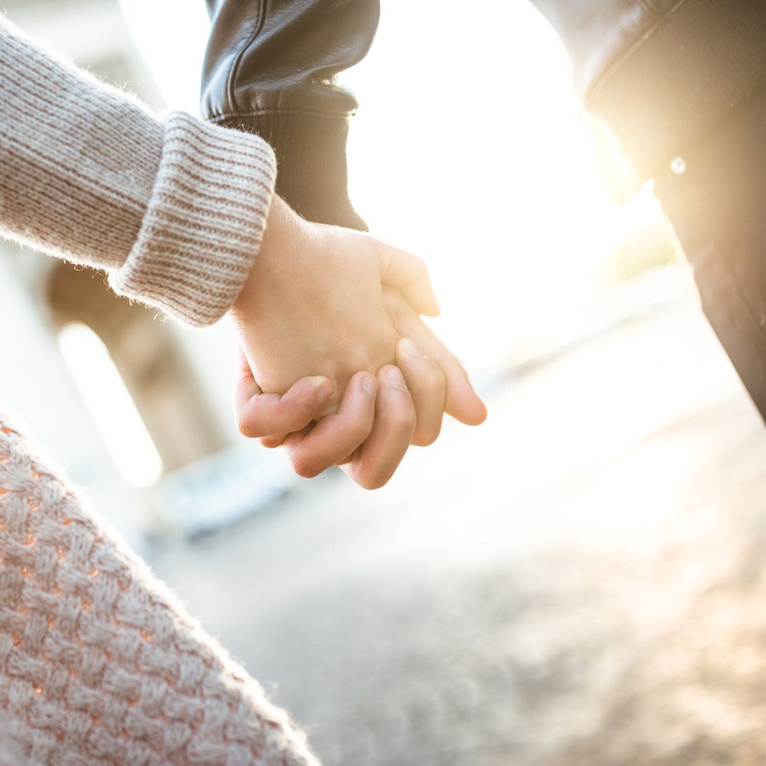 Un jeune couple marche main dans la main sous la lumière du soleil et partage des valeurs communes pour une relation durable.