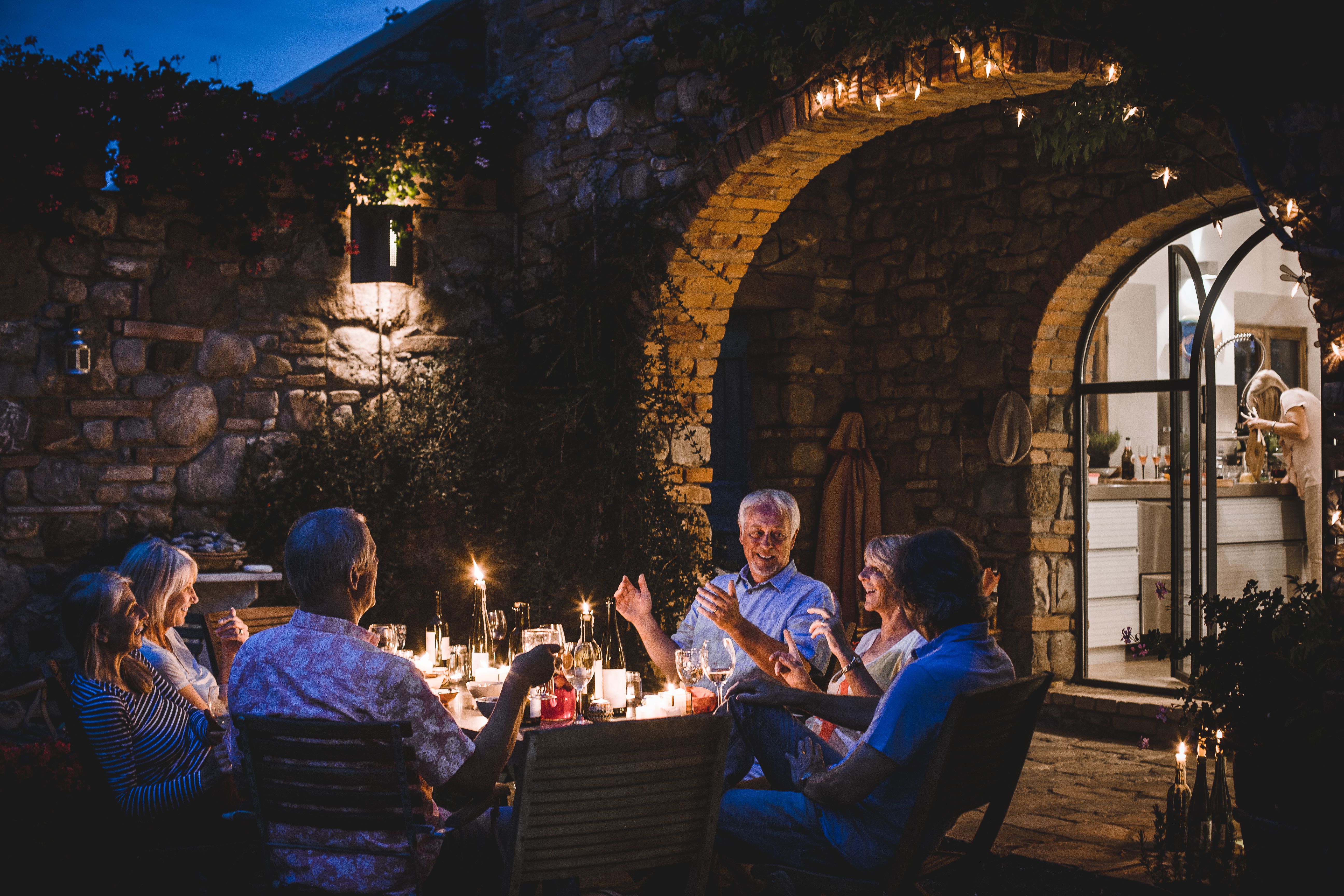 Groupe d’amis souriants partageant un dîner dans un jardin en soirée, illustrant un nouveau départ, des rencontres authentiques et la reprise d’une vie sociale après un divorce.